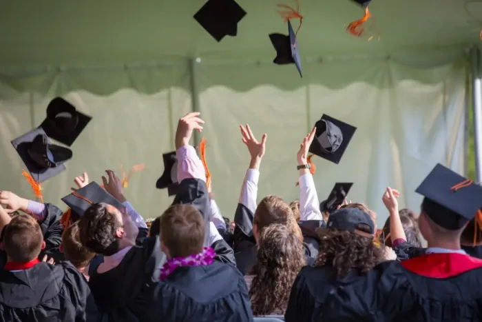 Group of college graduates celebrating with cap toss, symbolizing financial planning for education goals in Alpharetta GA